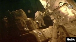 Esta foto proporcionada por la NASA muestra a los astronautas Bob Behnken y Chris Cassidy en una caminata espacial fuera de la Estación Espacial Internacional el martes 21 de julio de 2020.