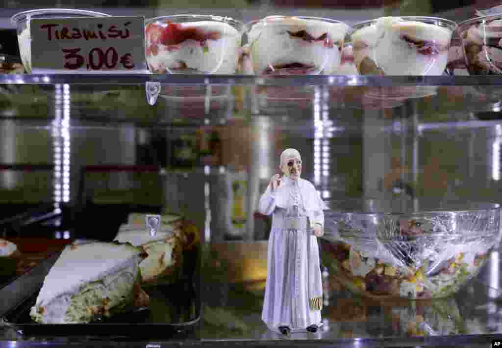 A statuette of Pope Francis is placed among desserts on sale at a cafe, in St. Peter's Square at the Vatican, April 27, 2014.