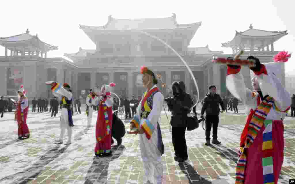 2012年12月12日，青少年在平壤大剧院前演奏，庆祝火箭发射成功。