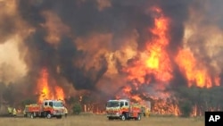 In this image dated Dec. 30, 2019, and provided by NSW Rural Fire Service via their twitter account, firefighters are seen as they try to protect homes around Charmhaven, New South Wales. Wildfires burning across Australia's two most-populous states…