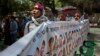 FILE - A Tibetan exile sings the national anthem as he holds a banner with others showing the portraits of Tibetan self-immolators during a protest in New Delhi, April 25, 2014.
