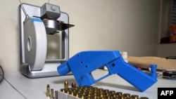 
Sebuah pistol Liberator tampak di sebelah pencetak 3-Dimensi yang mencetak komponen pistol, 11 Juli 2013.
