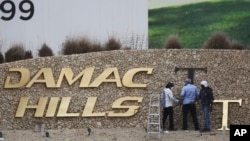 FILE- In this Sunday, Feb. 12, 2017 file photo, workers re-install a gold letter sign for the Trump International Golf Club in Dubai, United Arab Emirates.