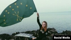 A Circassian woman waives the national flag on the Black Sea coast, May 21, 2016.