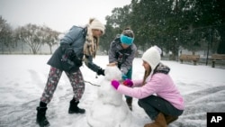 Children from the Hoffman and Lynns families build a snowman on the public basketball courts in Forsyth Park, Jan. 3, 2018, in Savannah, Georgia.