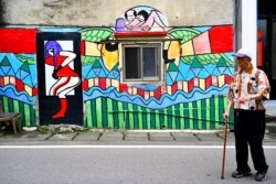 A local resident walks past a wall painted by Hakka graffiti artist Wu Tsun-hsien in the Taiwanese village of Ruan Chiao, March 30, 2019.