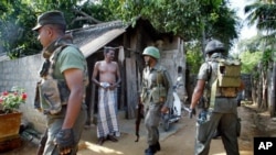 Seorang warga Tamil mengamati anggota tentara Sri Lanka yang sedang menggelar operasi pencarian di Jaffna pasca perang saudara di wilayah itu (Foto: dok). Partai utama suku Tamil mendesak PBB agar menebus kegagalan yang telah diakuinya dalam upaya melindungi warga sipil Tamil dengan memulai penyelidikan internasional (16/11).