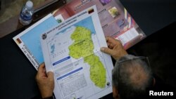 Un miembro de la Asamblea Nacional oficialista sostiene un mapa que muestra el Esequibo, territorio que Venezuela y Guyana se disputan. 