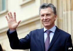 FILE - Argentina's President Mauricio Macri waves at journalists at the end of a welcoming ceremony at the Presidential Palace in Bogota, Colombia, June 15, 2016.