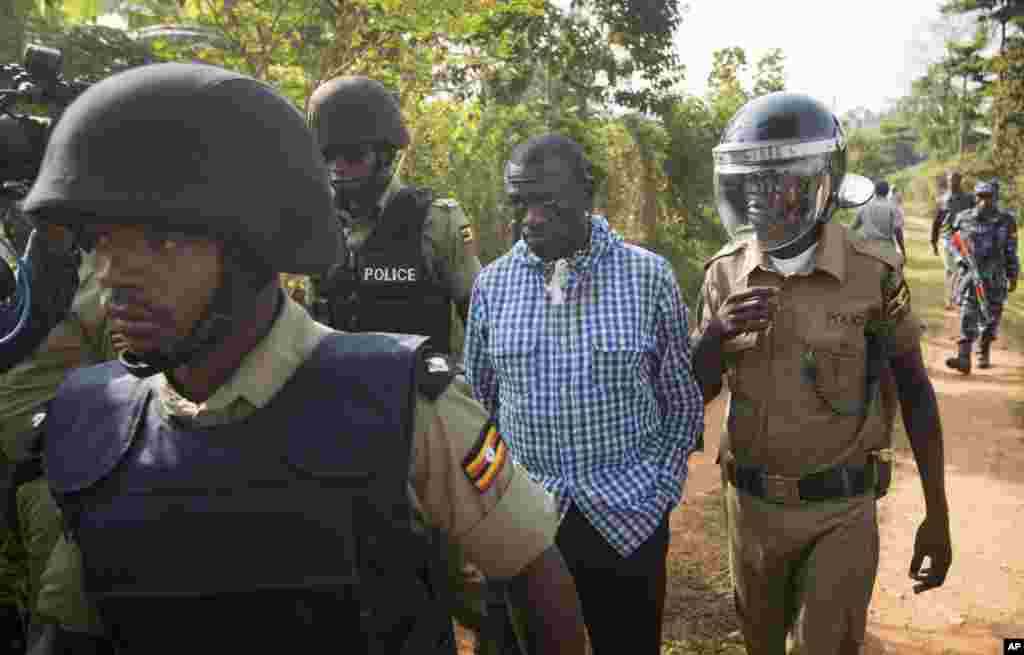 FILE - Uganda's main opposition leader Kizza Besigye, center, is arrested by police and thrown into the back of a blacked-out police van which whisked him away and was later seen at a rural police station, outside his home in Kasangati, Uganda, Feb. 22, 2