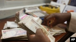 FILE - A money changer counts Nigerian currency in Lagos, Nigeria, Oct. 20, 2015. Switzerland has agreed to repatriate $321 million in stolen funds to Nigeria.