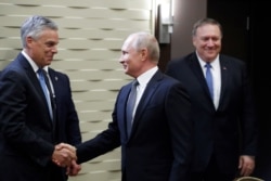 FILE - Russian President Vladimir Putin shakes hands with U.S. Ambassador to Russia Jon Huntsman as U.S. Secretary of State Mike Pompeo stands behind prior to their talks in the Black Sea resort city of Sochi, May 14, 2019.