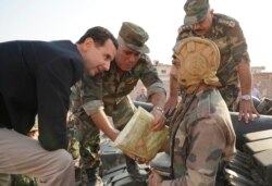 In this photo released on the official Facebook page of the Syrian Presidency, President Bashar Assad, left, speaks with Syrian troops during his visit to the strategic town of Habeet, in the northwestern province of Idlib, Oct. 22, 2019.