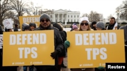 FILE - Demonstrators hold signs protesting the termination of Salvadorans' Temporary Protected Status, in front of the White House in Washington, Jan. 8, 2018.