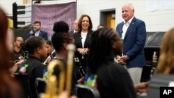 La candidata presidencial demócrata Kamala Harris y su compañero de fórmula, el gobernador de Minnesota, Tim Walz, hablan con miembros de la banda de música en la escuela secundaria Liberty County High School en Hinesville, Georgia, el 28 de agosto de 2024