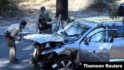 FILE - Los Angeles County Sheriff's Deputies inspect the vehicle of golfer Tiger Woods, who suffered multiple injuries in a single-vehicle crash in Los Angeles, California, Feb. 23, 2021. 