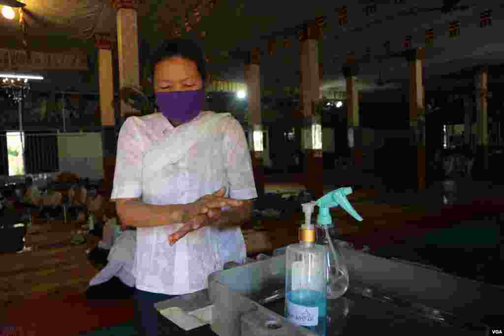 ស្រ្តី​ម្នាក់​កំពុង​លាង​ដៃ​នឹង​អាល់​កុល អំឡុង​​ពេល​​ប្រារព្ធ​ពិធី​បុណ្យ​ចូល​ឆ្នាំ​ខ្មែរ​ថ្ងៃទី​២ ​​នៅ​វត្ត​​ថាន់​ រាជធានី​ភ្នំពេញ នៅ​ថ្ងៃ​ទី​១៤ ខែមេសា ឆ្នាំ​២០២០។ (កាន់ វិច្ឆិកា/VOA)