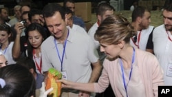 Suriya rahbari Bashar al-Assad va uning rafiqasi Asma poytaxt Damashqda Hims ahli uchun insonparvarlik yordamini taxlamoqda, 16-aprel, 2012-yil