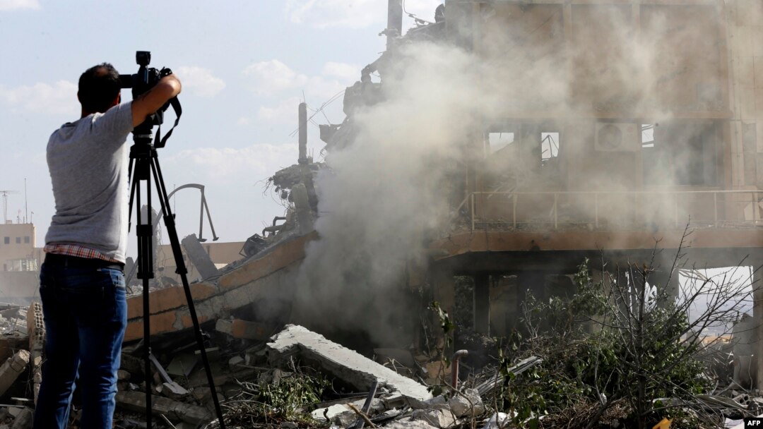 A journalist films the wreckage of a building described as part of the Scientific Studies and Research Centre (SSRC) compound in the Barzeh district, north of Damascus, during a press tour organized by the Syrian Information Ministry, on April 14, 2018.
