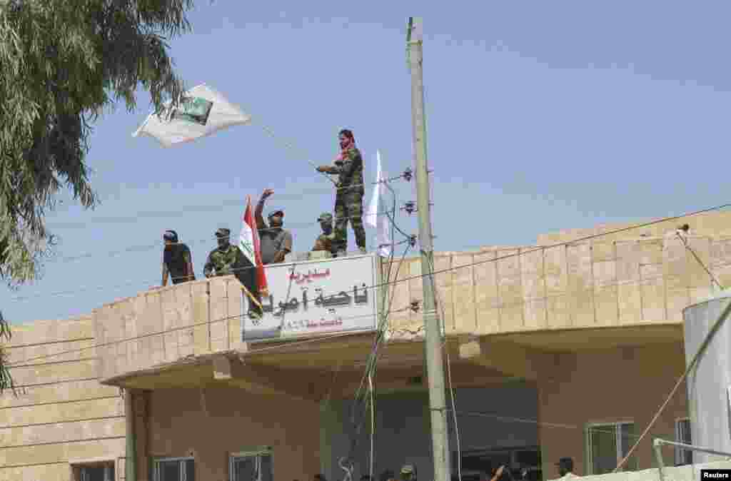 Triumphant Iraqi Shiite militia fighters celebrate breaking a long siege of Amerli by Islamic State militants, Sept. 2, 2014.