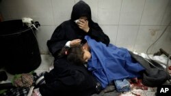 Una mujer palestina llora sentada junto a su niña herida en el bombardeo israelí de la Franja de Gaza mientras recibe tratamiento en el hospital Nasser en Khan Younis, en el sur de la Franja de Gaza, el lunes 22 de enero de 2024.