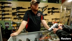 FILE - A store employee speaks to a customer about the purchase of a 9 mm handgun in Bridgeton, Missouri, Nov. 13, 2014.
