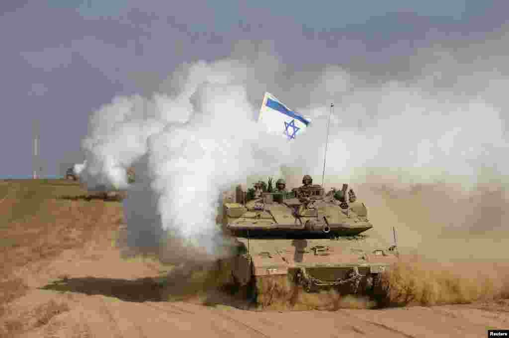 An Israeli soldier gestures from atop a tank after crossing the border back into Israel. Israel pulled its ground forces out of the Gaza Strip at the start of a 72-hour ceasefire with Hamas, Aug. 5, 2014. 