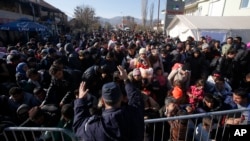 FILE - Serbian police officer attempt to organize migrants queuing to get registered at a refugee center in the southern Serbian town of Presevo, Nov. 16, 2015. 