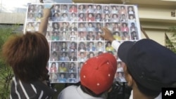 A Cambodian man compares a photo to those of stampede victims at Preah Kossamak Hospital in Phnom Penh, Cambodia, 24 Nov 2010.