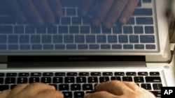 FILE - A photo illustration shows hands typing on a computer keyboard in California. 