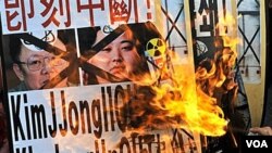 Warga Korea Selatan melakukan protes dengan membakar poster Kim Jong-il, dan puteranya Kim Jong-un di Seoul, 28 Desember 2010.