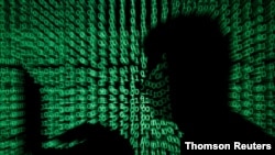 Un hombre sostiene una computadora portátil mientras el código cibernético se proyecta sobre él en esta imagen de ilustración.