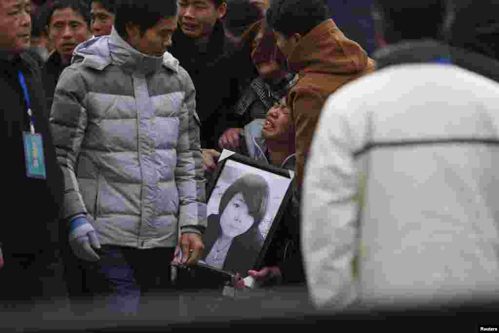 Relatives cry as they hold a picture of a victim of the stampede incident during a New Year's celebration at the Bund, a waterfront area of Shanghai, China, Jan. 6, 2015.