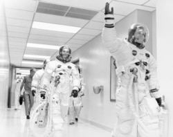 FILE - Apollo 11 astronaut Neil Armstrong waves to well-wishers on the way out to the transfer van, Cape Canaveral, Florida, July 16, 1969. Mike Collins and Buzz Aldrin follow Armstrong down the hallway.