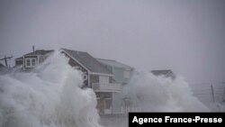File - Waves crash over oceanfront homes during a nor’easter in Scituate, Massachusetts on January 29, 2022.