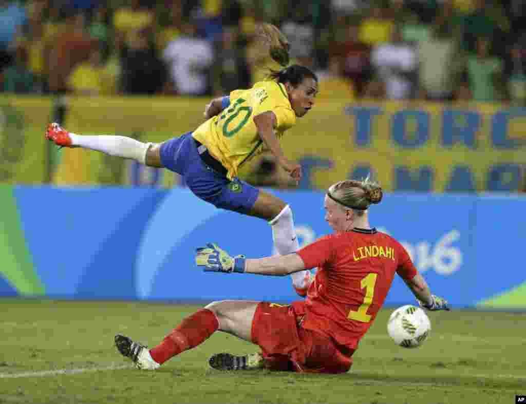 Brazil's Marta, left, leaps over Sweden goalkeeper Hedvig Lindahl as she attempts a shot on goal during a group E match of the women's Olympic football tournament between Sweden and Brazil at the Rio Olympic Stadium.