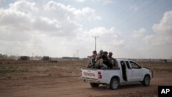 Pasukan kelompok Hamas Palestina dengan mengendarai truk berpatroli di perbatasan dengan Israel dekat Khan Younis, kota di sebelah selatan Jalur Gaza, 10 Juni 2015. Buldoser militer Israel tampak dari kejauhan.
