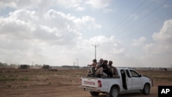 FILE - In this June 10, 2015 photo, Palestinian Hamas gunmen ride on the back of a pick-up truck as they patrol the border with Israel near the southern Gaza Strip town of Khan Younis. 