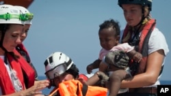 Rescuers put a life jacked on a child during a search and rescue operation conducted by SOS Mediterranee and MSF (Doctors Without Borders) NGOs, in the Mediterranean Sea, north of Libyan coast.