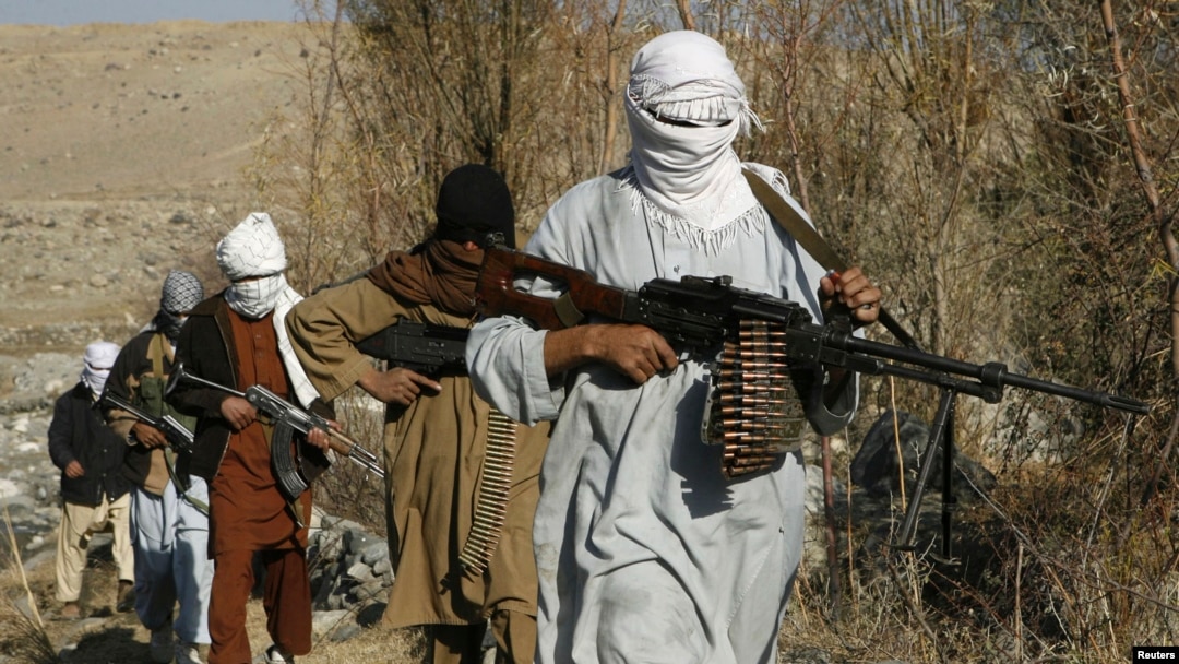 FILE - Taliban fighters carry weapons in an undisclosed location in Nangarhar province.