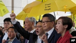 "Occupy Central" leaders, from right, Tanya Chan, Chan Kin Man, Benny Tai, Chu Yiu Ming and Lee Wing Tat shout slogans before entering a court in Hong Kong, Nov. 19, 2018.