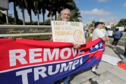 FILE - Ray Bonachea holds a sign in favor of the impeachment of President Donald Trump, outside the Trump National Doral Miami golf resort, Dec. 17, 2019, in Doral, Fla.