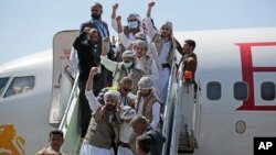 Tahanan Yaman mengepalkan tangan saat tiba di bandara di Sana'a setelah dibebaskan oleh koalisi pimpinan Saudi. (Foto: AP)