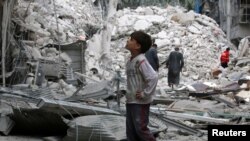 FILE - A boy inspects a damaged site after airstrikes on the rebel held Tariq al-Bab neighbourhood of Aleppo, Syria, Sept. 23, 2016. 