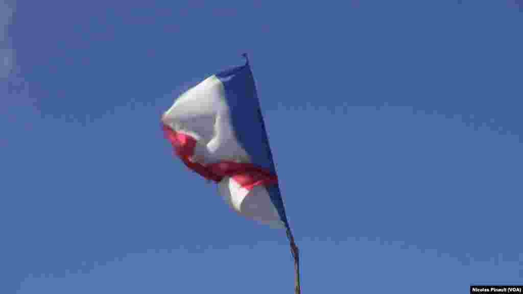 Le drapeau français flotte au-dessus d'une tente dans la "jungle". Ce camp est situé aux abords de Calais dans le nord de la France, 13 octobre 2015 (Nicolas Pinault/VOA). 
