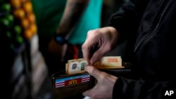 ARCHIVO - Un comprador paga en efectivo por verduras en un mercado de Buenos Aires, Argentina, el 1 de septiembre de 2023. Los argentinos luchan contra una de las tasas de inflación más altas del mundo.