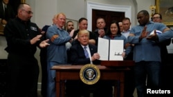 FILE - U.S. President Donald Trump is applauded by U.S. industry workers after signing a proclamation to establish tariffs on imports of steel and aluminum, at the White House in Washington, March 8, 2018.