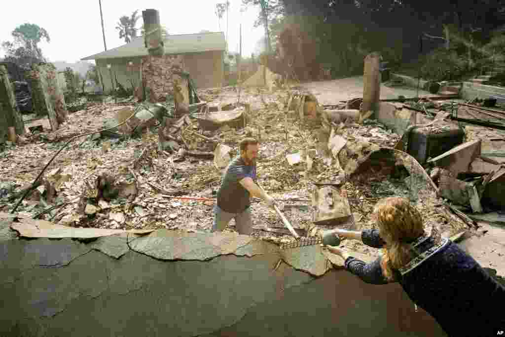 Paul Mattesich hands a jar to his wife Erica Mattesich while sifting through rubble at his family's home in Ventura following a wildfire, Dec. 6, 2017.