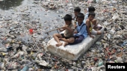 Anak-anak bermain di atas sungai yang penuh sampah di daerah kumuh di Jakarta. (Foto: Dok)