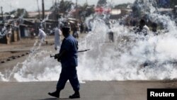 FILE - A policeman walks away after throwing a tear gas canister during a protest against Burundian President Pierre Nkurunziza and his bid for a third term in Bujumbura, June 2, 2015.